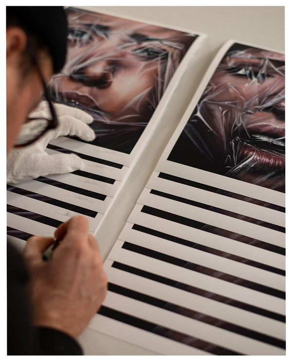Sebastian Wandl is signing off a couple of his plastic suffocation mini prints by hand.