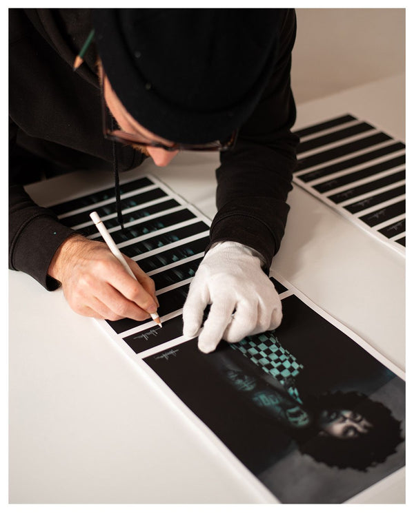Sebastian Wandl is signing off a couple of his mini prints from the trash me collection. You see a woman who is covered in water because of global warming.